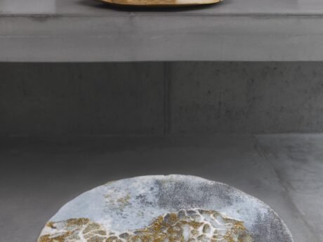 Stack of pastel towels on a wooden tray atop a gray counter, with books to the right and a patterned circular rug on the floor.