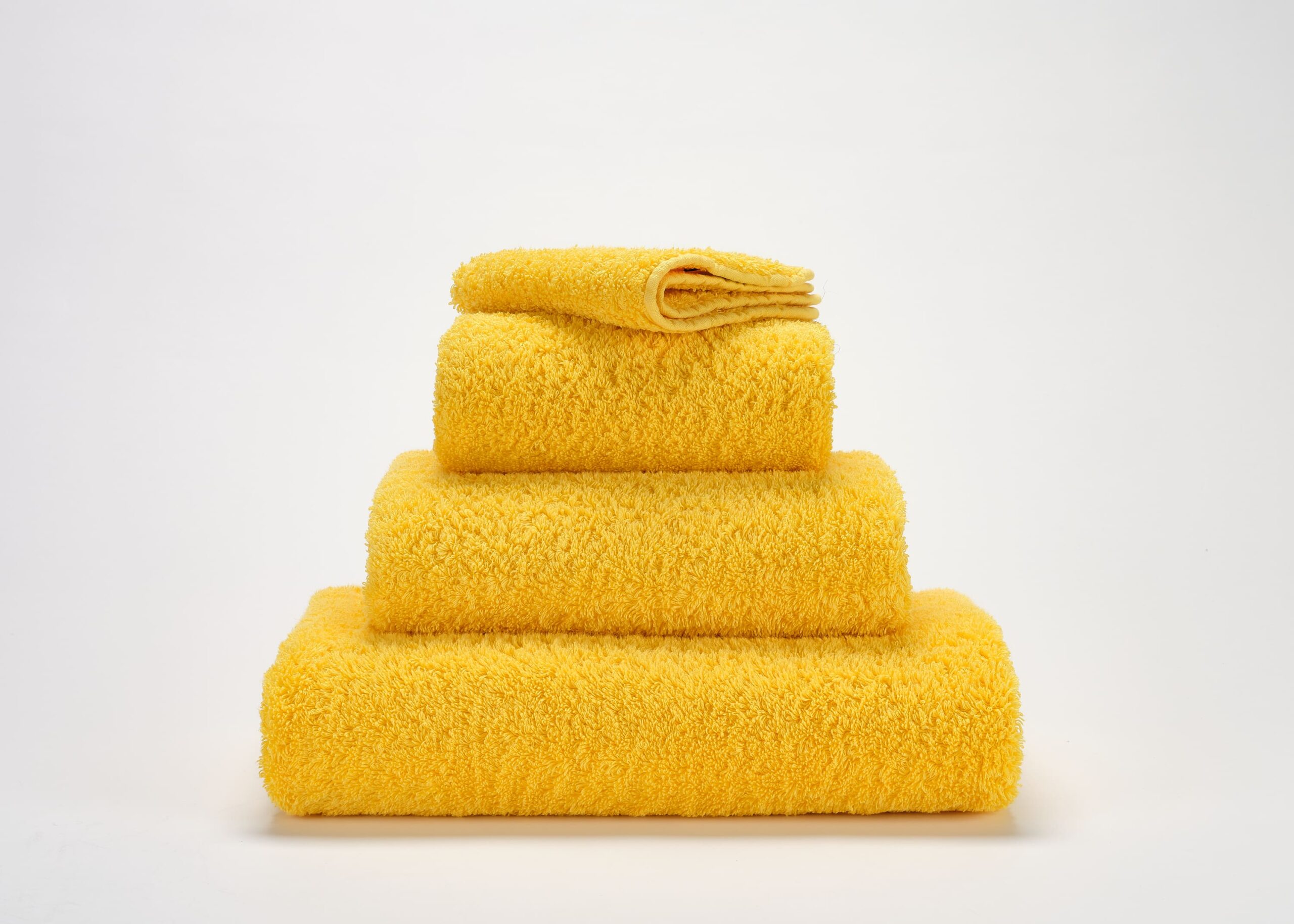 Abyss & Habidecor Super Pile 830 luxury cotton towels in golden yellow stacked