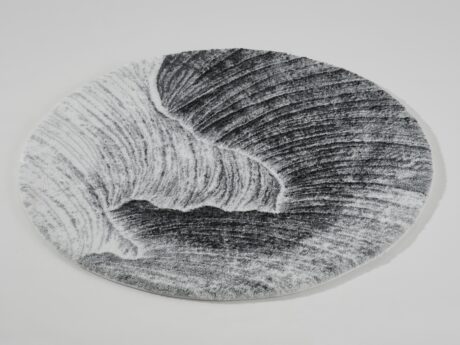Round shag rug with a swirling black-and-white pattern on a light surface.