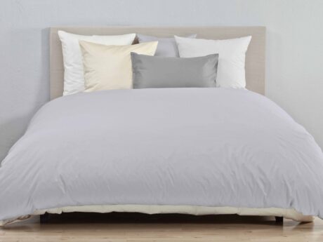 Christian Fischbacher Percale Uni bed linen styled on double bed with percale duvet cover and mixed solid colour pillowcases in grey, ivory and white, minimal bedroom interior